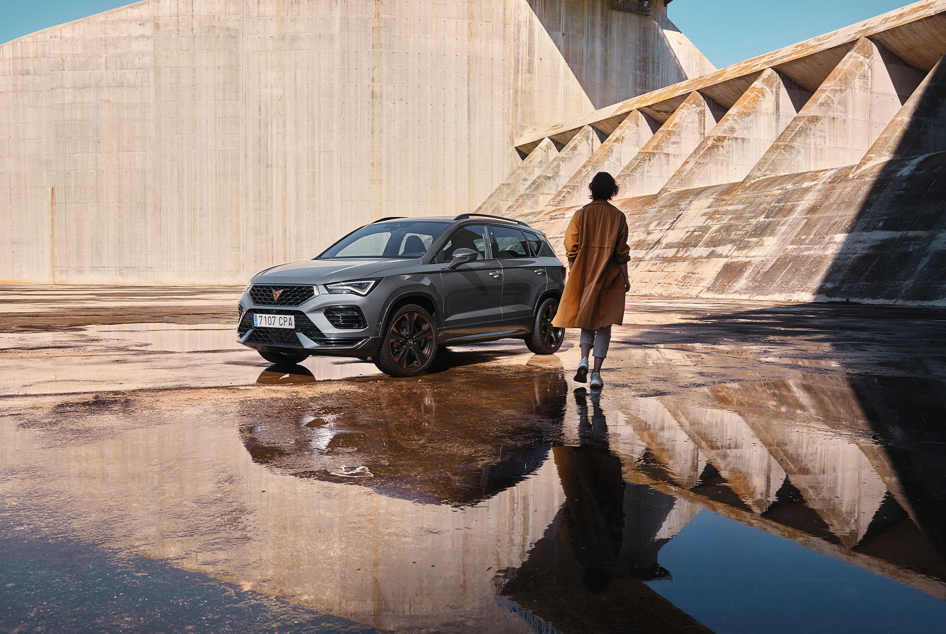 A person walking towards a CUPRA Ateca, showcasing the car's bold, athletic lines and dynamic form, representing the CUPRA tribe's spirit. 