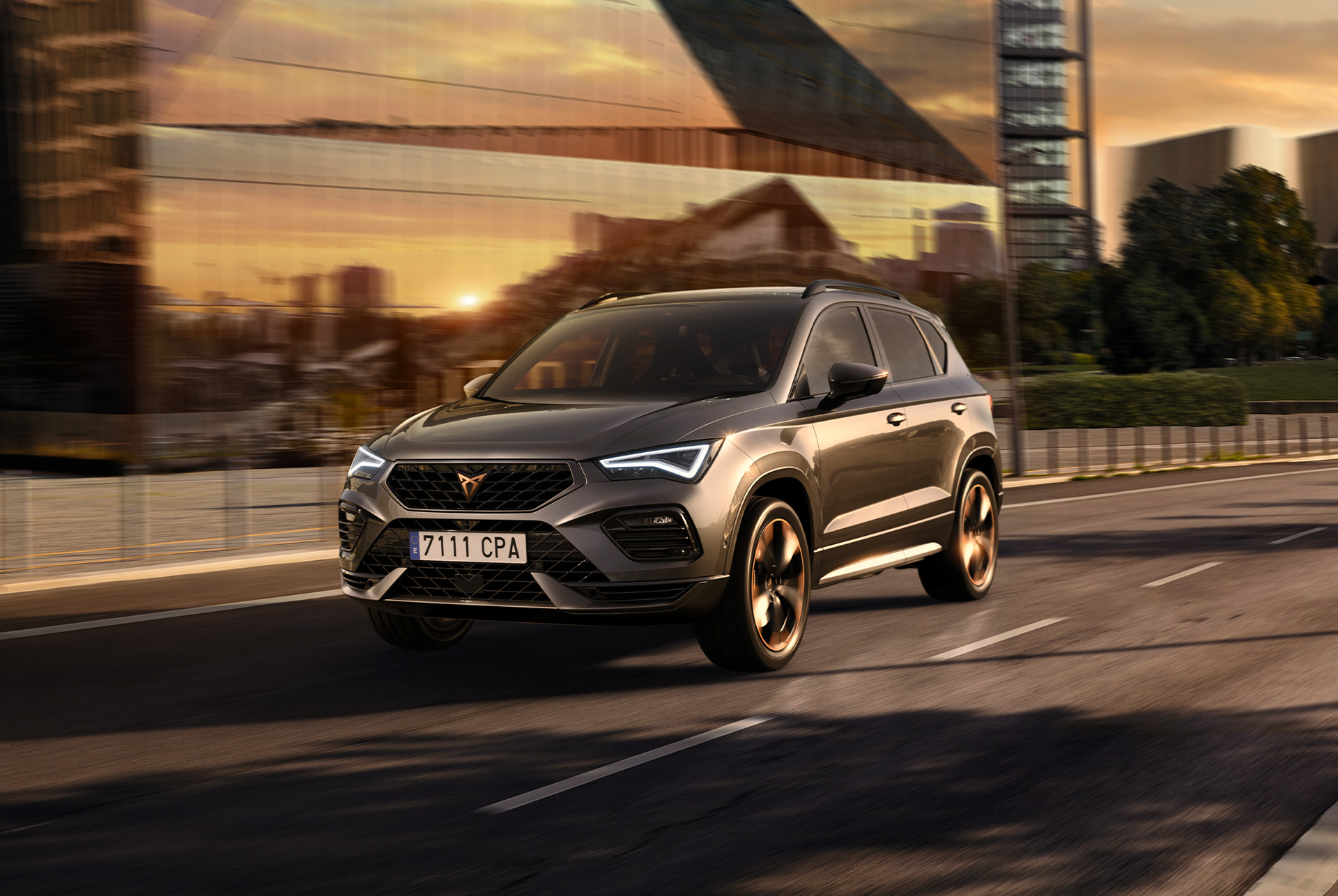 A grey cupra ateca suv displayed against a white background. The car features a bold front grille, led headlights and copper accent alloy wheels, highlighting its sporty car design.